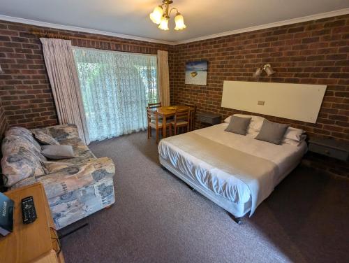 a bedroom with a bed and a chair and a table at Barham Colonial Motel in Barham