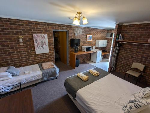 a bedroom with two beds and a brick wall at Barham Colonial Motel in Barham