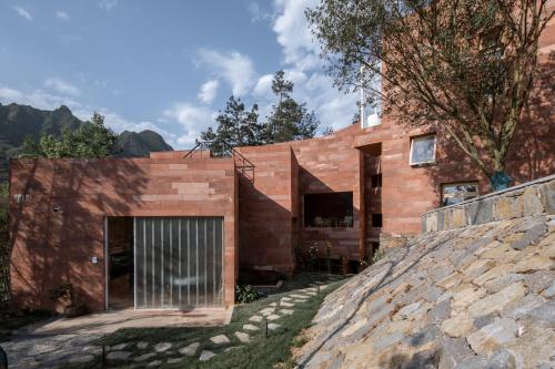 a brick house with ajar doors and a stone wall at Vretreats Suyunjian Boutique Hotel in Xinglong