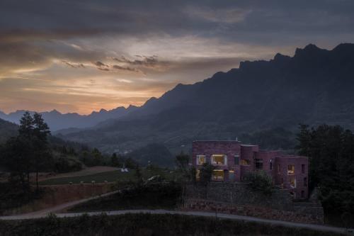 a house on a hill with mountains in the background at Vretreats Suyunjian Boutique Hotel in Xinglong