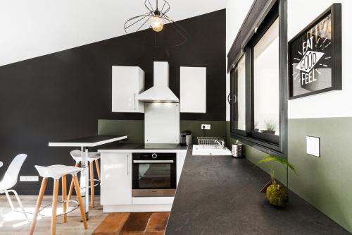 une cuisine avec des murs noirs et des appareils blancs dans l'établissement Chaleureux T2 centre ville au calme et patio, à Toulouse