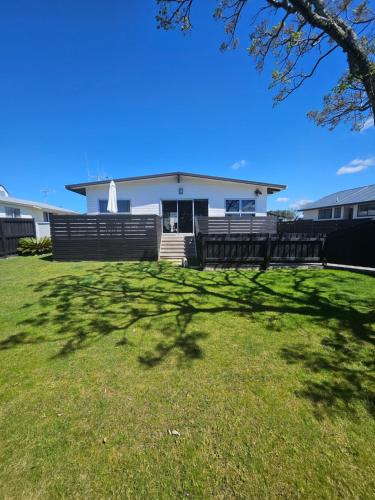 a large shadow of a tree in front of a house at Ultimate Family Holiday - Pet Friendly! in Papamoa