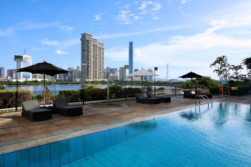 a pool with chairs and umbrellas on top of a building at Marco Polo Xiamen in Xiamen