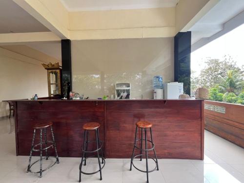 a kitchen with two stools at a wooden bar at Ubud Suites Batuan near Tegenungan Waterfall in Sukawati