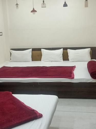 a large bed with red sheets and white pillows at Hotel star villa INN in Ujjain