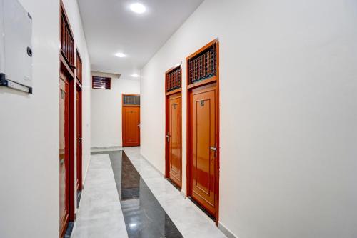 a corridor with wooden doors in a house at Hotel O Conifer INN in Meerut