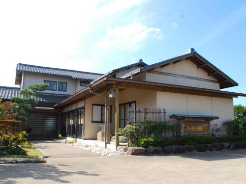a japanese house with a gate and a driveway at Minshuku Shima in Kaga