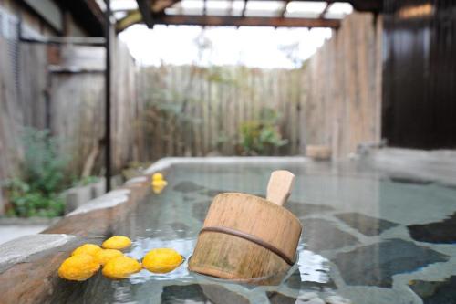 a wooden paddle in a tub of water with lemons in it at Secret Base Tokinokakera in Yufuin