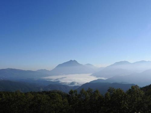 a misty valley with mountains in the distance at Secret Base Tokinokakera in Yufuin