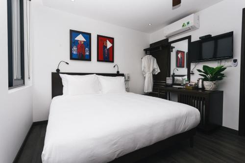 a bedroom with a white bed and a television at Le Petit Villa Hoi An in Hoi An