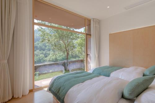two beds in a room with a large window at Vretreats Suyunjian Boutique Hotel in Xinglong