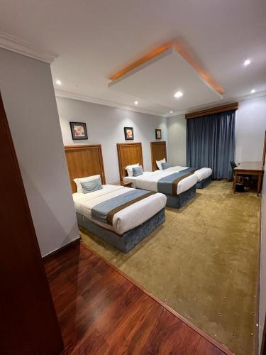 two beds in a room with wooden floors and a room with at Al Masem Serviced Apartments - Gharnata - Exit 9 in Riyadh
