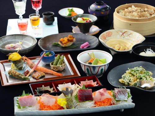 a table topped with different types of food on plates at Luxury Wa Hotel Kaze No Kaori in Ito