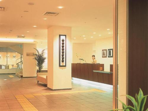 a man in a lobby with a reception desk at Ou Hotel in Yonago