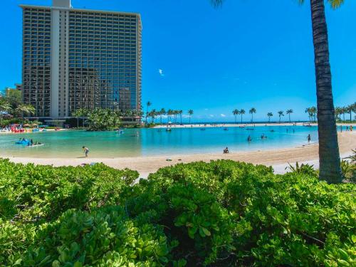 a beach with palm trees and people in the water at Newly Renovated Oceanfront Waikiki- Ilikai Marina in Honolulu