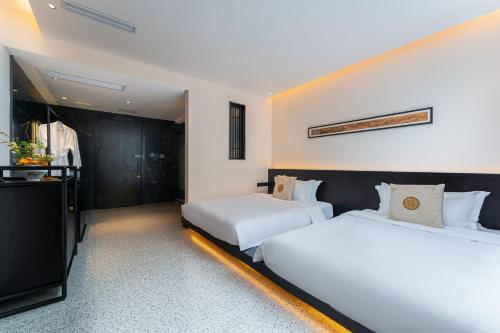 two beds in a hotel room with white sheets at Yangshuo Mountain Vista Courtyard in Yangshuo