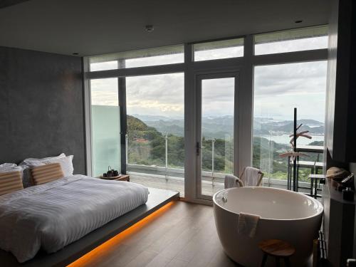 a bedroom with a tub and a bed and a window at Daybreak in Jiufen