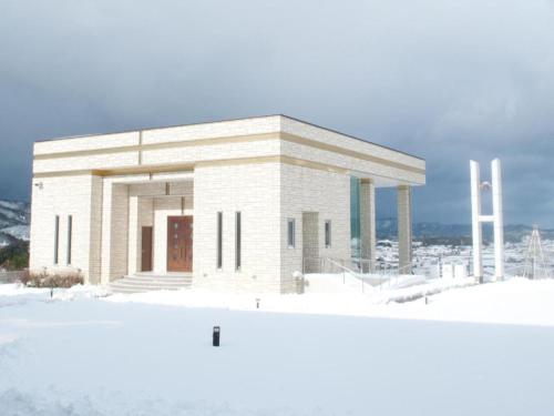 a large white building in the snow with snow at Centrale Hotel Kyotango in Kyotango