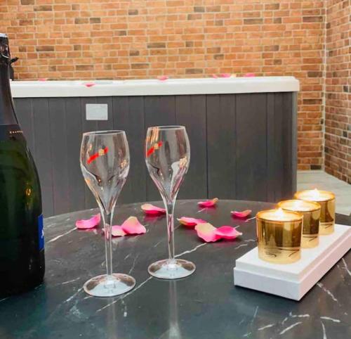 deux verres à vin assis sur une table avec des pétales roses dans l'établissement Love room - Parenthèse romantique avec spa privé, au Perrier