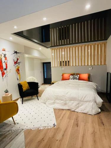 - une chambre avec un grand lit et une chaise noire dans l'établissement Love room - Parenthèse romantique avec spa privé, au Perrier