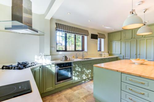 a kitchen with green cabinets and a wooden counter top at Oldfield house, walking distance of pub & sea in West Itchenor