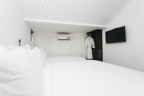 a white room with a bed and a tv at Le Petit Villa Hoi An in Hoi An