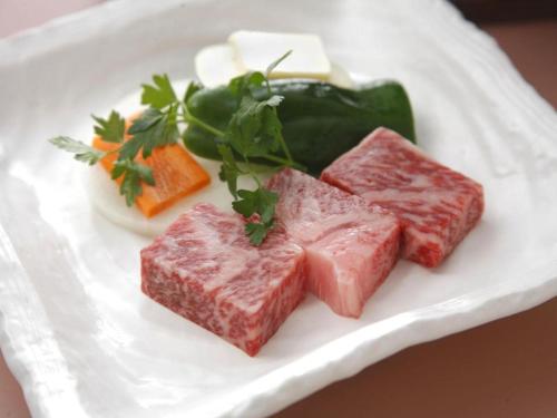 a plate of meat and vegetables on a white plate at Kuju Kogenso Hotel in Kokonoe