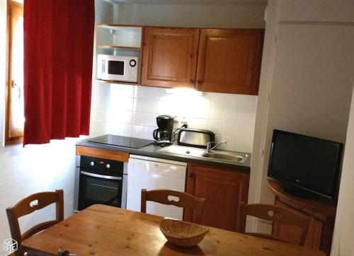 une cuisine avec une table en bois et une cuisine avec un évier et un four micro-ondes dans l'établissement Superdévoluy Superbe appartement 6 places avec parking, à Saint-Étienne-en-Dévoluy
