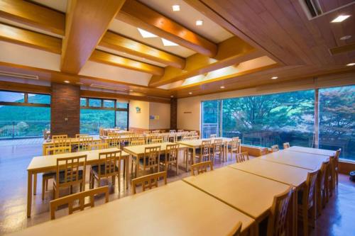 una classe con tavoli e sedie in una stanza con ampie finestre di Yufuin Onsen Yufuin Nanairo no Kaze a Yufu