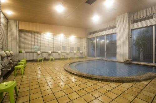 - une piscine dans une pièce avec des chaises et une table dans l'établissement Washigatake Kogen Hotel Rainbow, à Seki