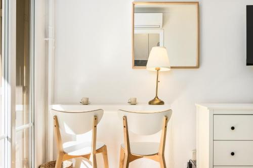 une table blanche avec deux chaises et une lampe dans l'établissement Studio moderne, à Menton