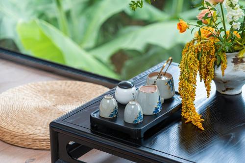 a black table with a vase with flowers on it at Yangshuo Mountain Vista Courtyard in Yangshuo