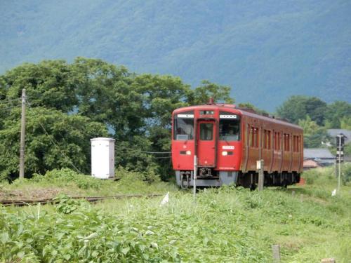 a red train is traveling down the tracks at Yufuin Matousou in Yufuin