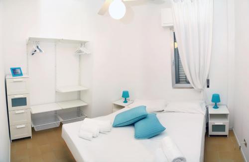 a white room with two beds with blue pillows at Kaary Bella Vista in Marina di Ragusa