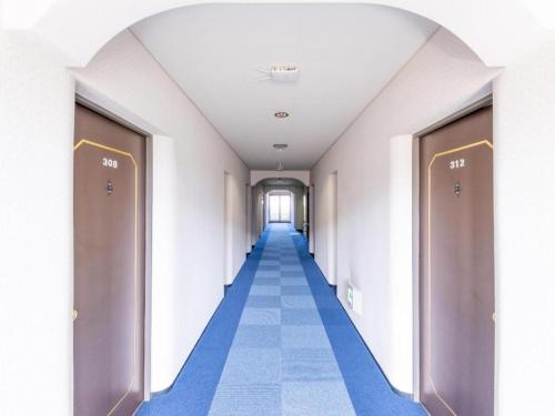 an empty corridor of a hospital hallway with blue floors and doors at Tabist Hotel Sankoen in Hitachi