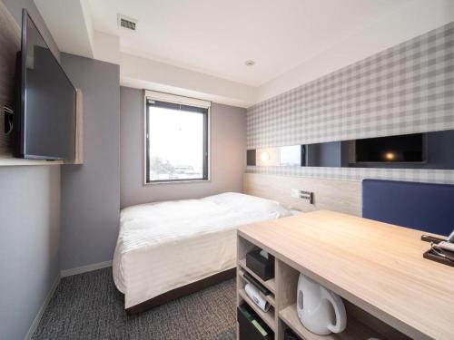 a bedroom with a bed and a flat screen tv at Super Hotel anashiyakusyomae in Anan