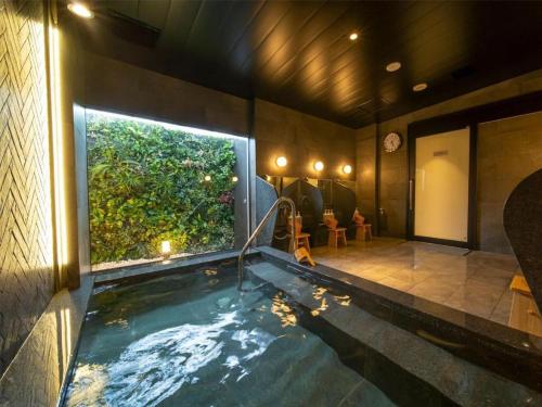 a large indoor swimming pool with a large window at Super Hotel anashiyakusyomae in Anan