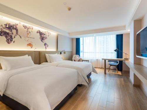 two beds in a hotel room with a world map on the wall at Echarm Hotel - Foshan Sanshui Wanda Plaza in Sanshui