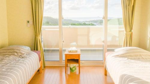 a bedroom with two beds and a large window at セイントS Saint-S in Motobu