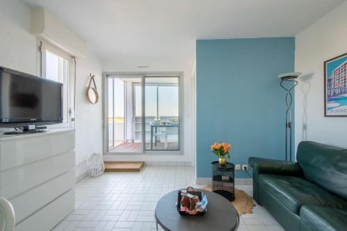 un salon avec un canapé et une télévision à écran plat dans l'établissement Sérénité à la Mer Vue Mer d'exception Parking Privé Clim wifi fibre, à La Grande Motte