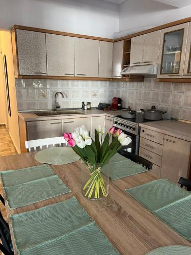a kitchen with a table with a vase of flowers on it at Dimitris Family Apartment in Nea Moudania