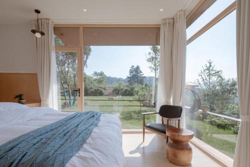 兴隆Vretreats Suyunjian Boutique Hotel的卧室配有一张床和一张椅子,位于窗户前
