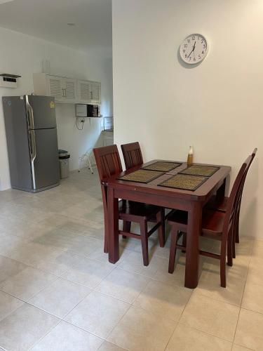 a dining room table with chairs and a clock on the wall at Samui Green Life in Bophut 