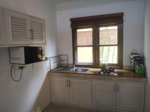 a kitchen with a sink and a microwave and a window at Samui Green Life in Bophut 