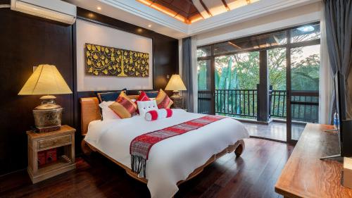 a bedroom with a large bed and a balcony at 西双版纳凤栖墅隐世 in Jinghong