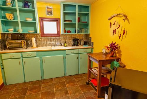 a kitchen with green cabinets and a yellow wall at Hayduke's Hideout in Moab