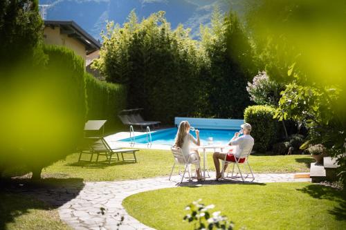 a man and woman sitting at a table in a garden at Weingarten Terlan - Rooms & Breakfast in Terlano