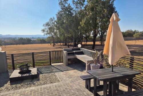a picnic table with an umbrella and a bench at Hornbill Self Catering Cottages Muldersdrift in Krugersdorp