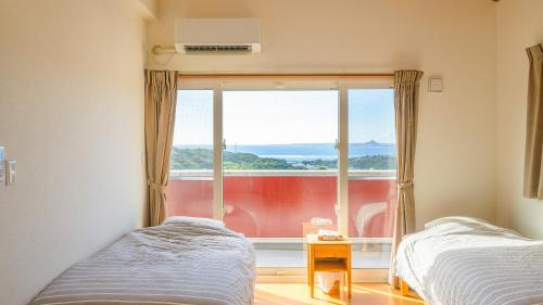 two beds in a room with a large window at セイントY saint-Y in Motobu