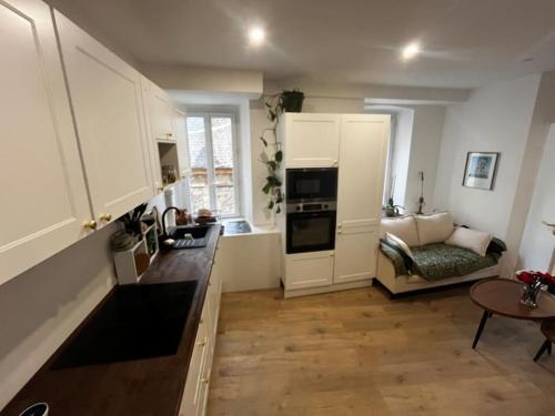 a kitchen with white cabinets and a living room at Chez Manon - Le Cocon Zen in Rumilly
